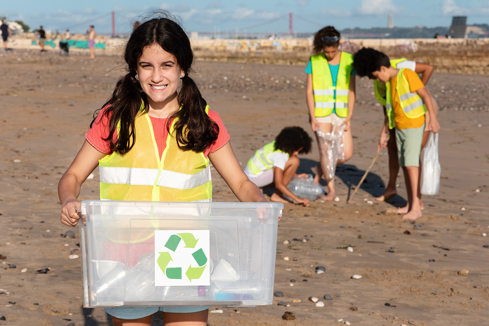 Smiling teen arab girl carries box for recycling, multiethnic children volunteers in vests collect garbage
